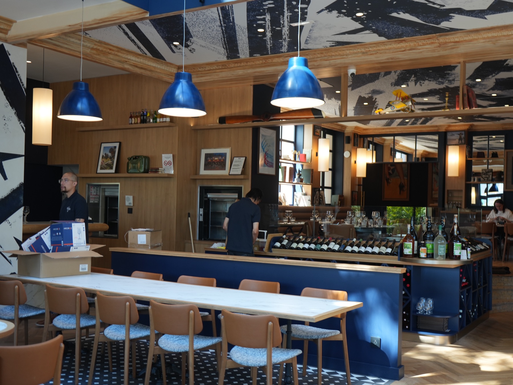 Bar & Bistrot — comptoir bleu, lampes industrielles et fresque signature de la Brasserie Les Officiers