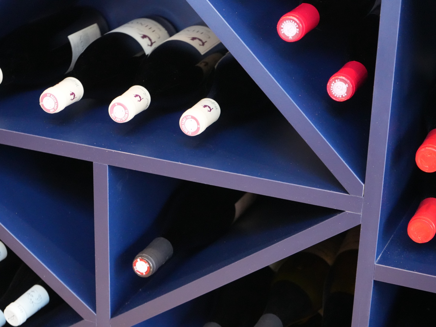 Cave à vin bleue avec bouteilles rangées en triangle · sélection vins de la Brasserie Les Officiers