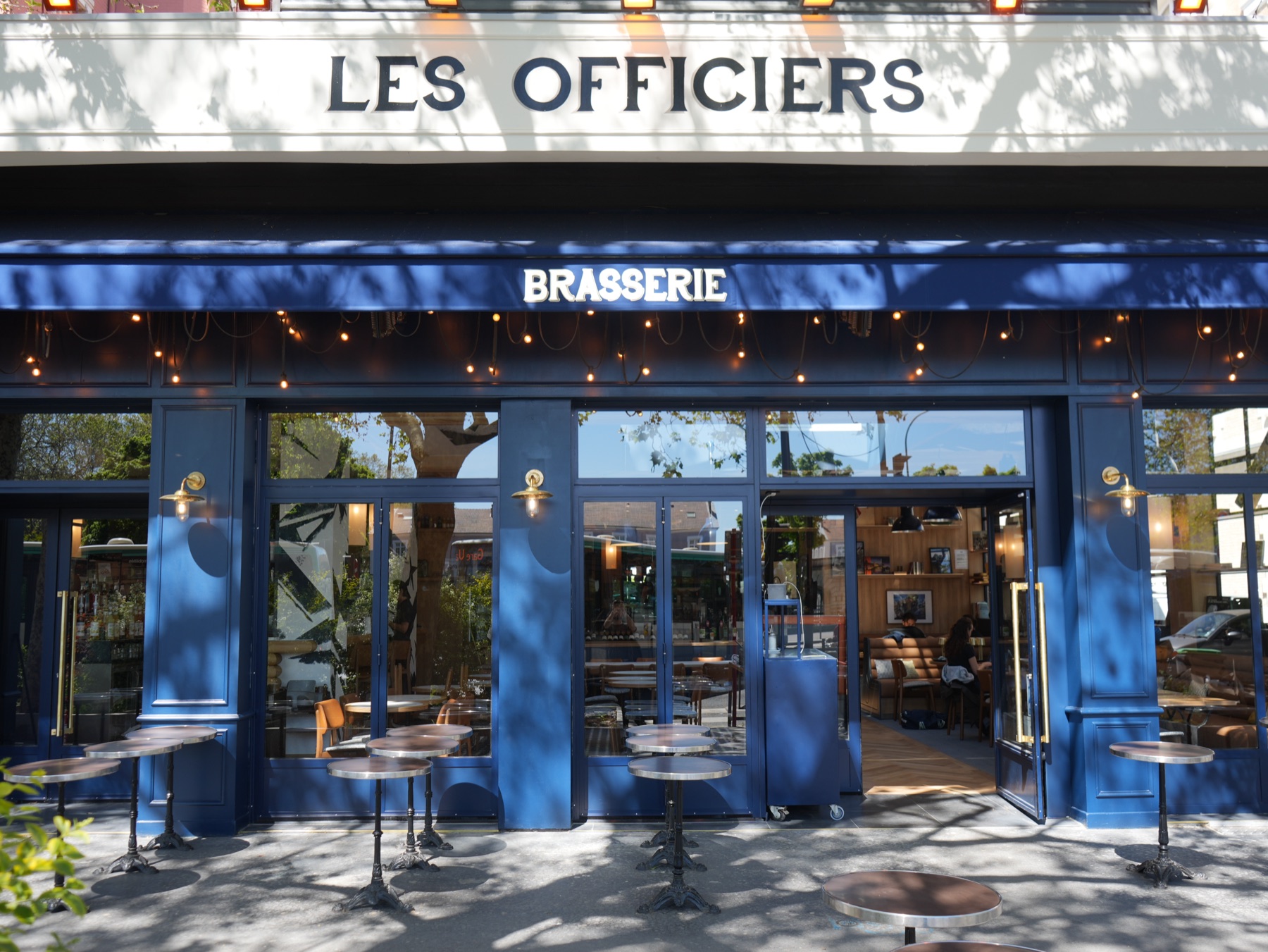 Devanture de la Brasserie Les Officiers à Vincennes · enseigne bleue, terrasse et tables extérieures