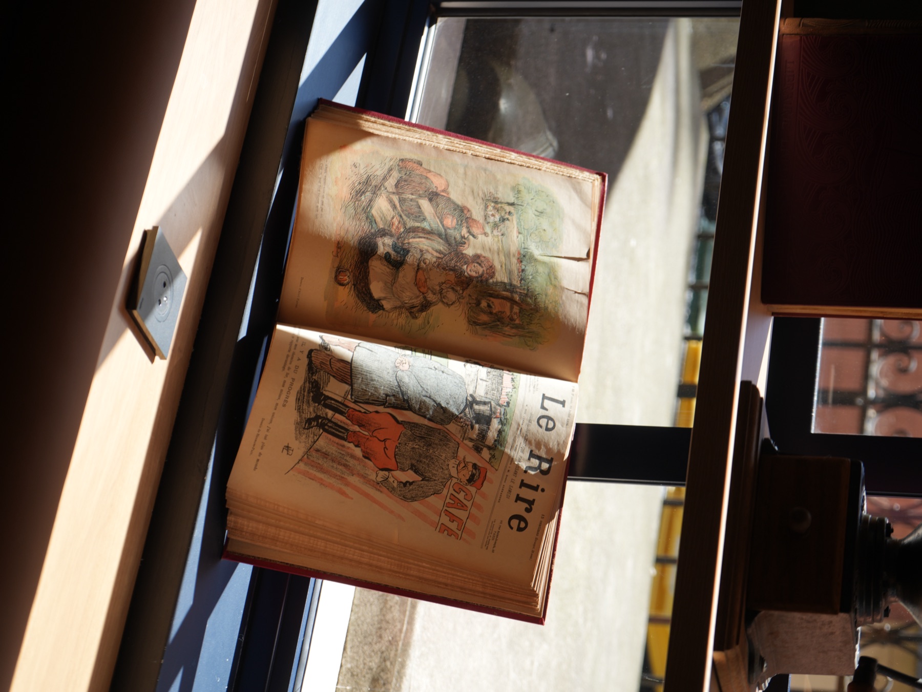 Livre vintage « Le Rire » posé devant une fenêtre · détail décoratif de la Brasserie Les Officiers